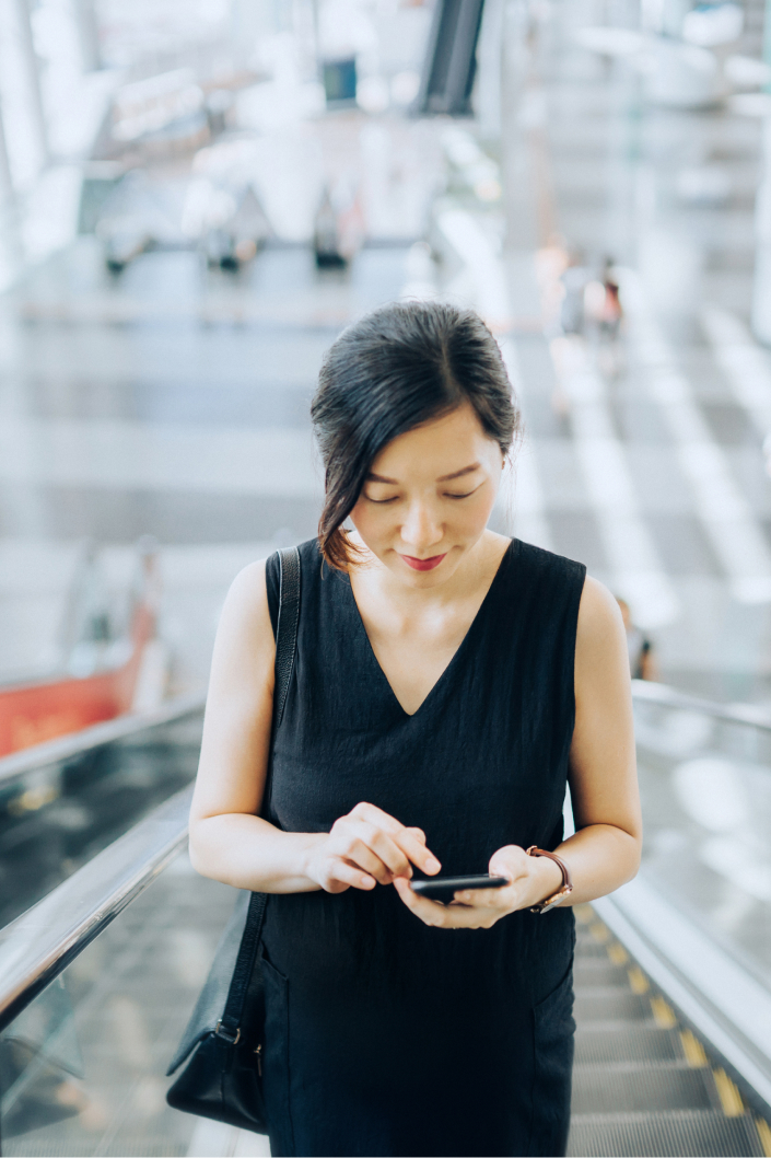 A woman viewing her mobile phone on an escalator